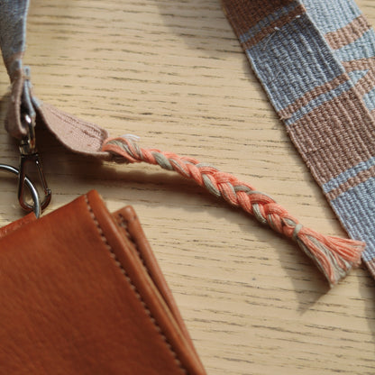 Brown leather pouch with plaid strap on a wooden surface
