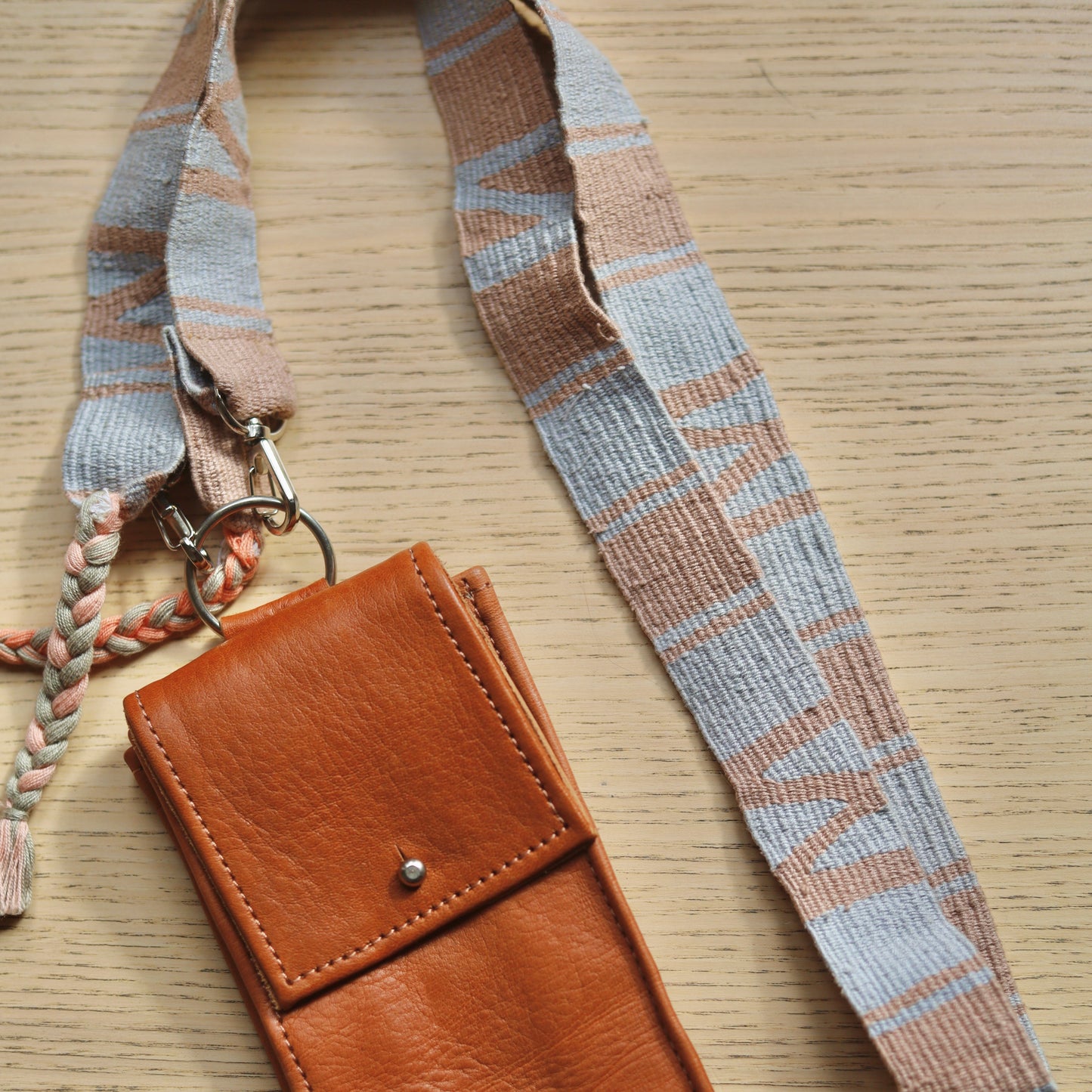 Brown leather phone case with lanyard on a wooden surface
