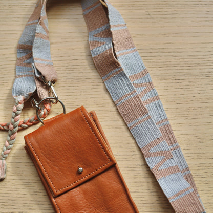 Brown leather phone case with lanyard on a wooden surface
