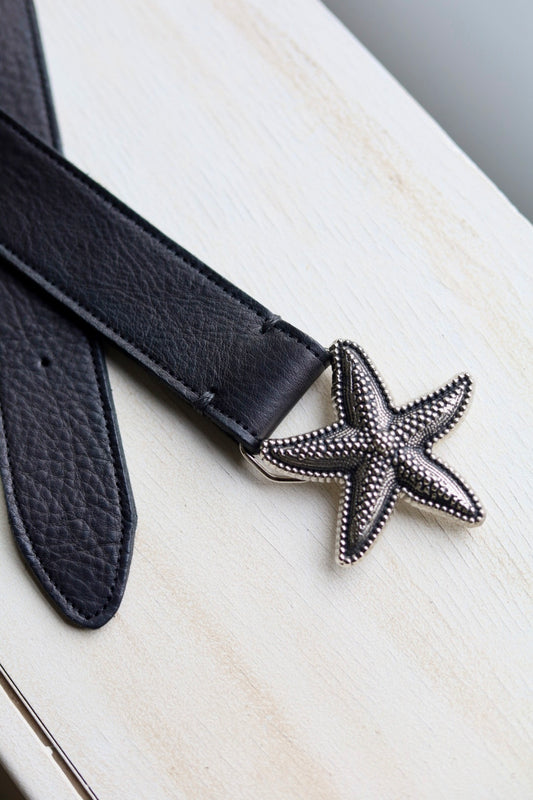 Black belt with a starfish-shaped buckle on a wooden surface