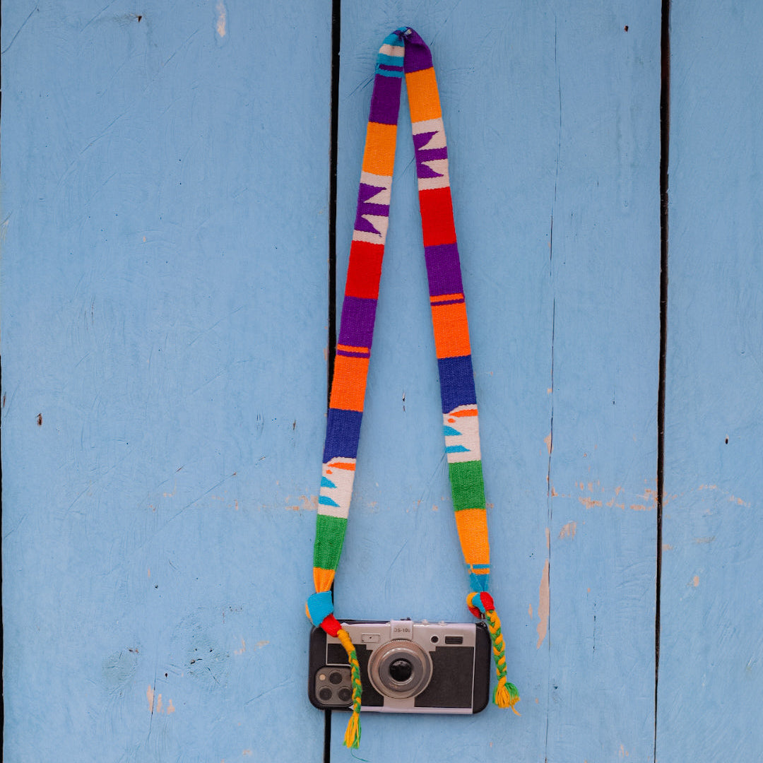 Colorful camera strap with a camera on a blue wooden surface