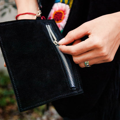 Person holding a black clutch with a floral background