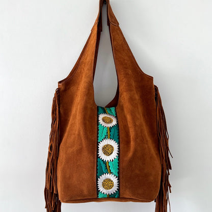 Brown suede handbag with floral embroidery and fringe on a white background