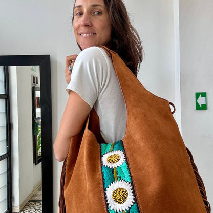 Woman wearing a brown suede bag with floral embroidery