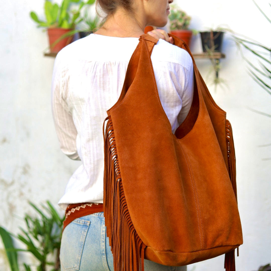 Woman wearing a brown suede bag with fringe in an outdoor setting