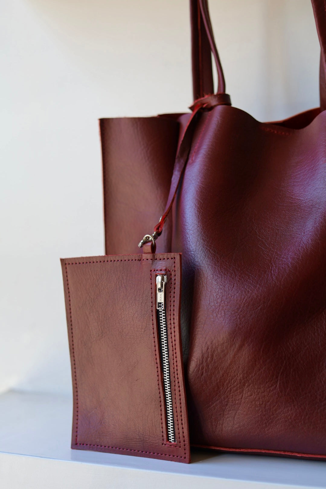 Brown leather tote bag with a matching phone case on a light background