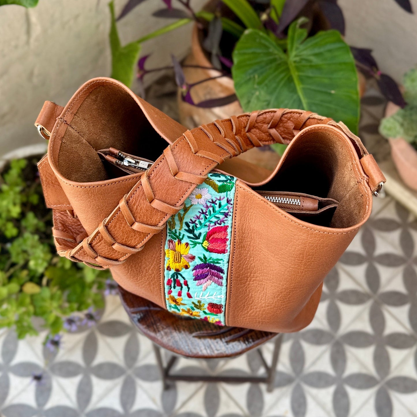 Brown woven bag with colorful fabric interior on a patterned floor