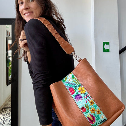 Woman holding a brown tote bag with floral patchwork design.