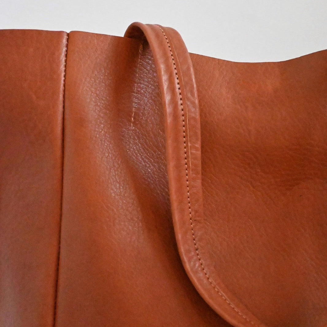 Close-up of a brown leather bag with a white background