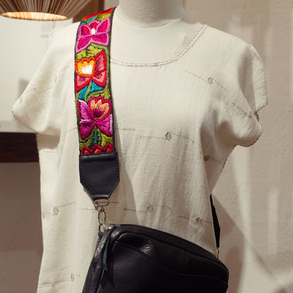Black bag with a colorful strap on a mannequin against a neutral background