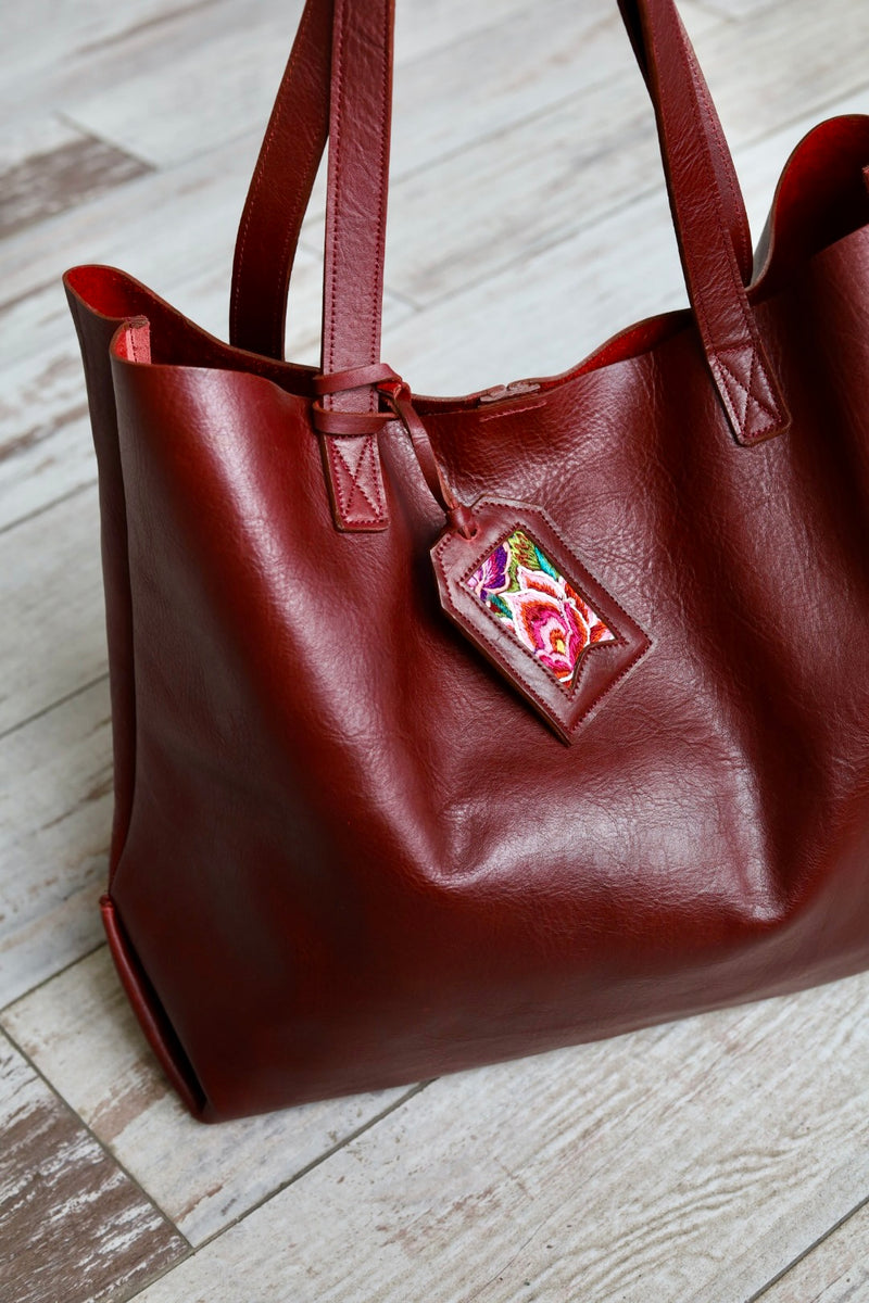 Brown leather handbag with a colorful tag on a wooden floor