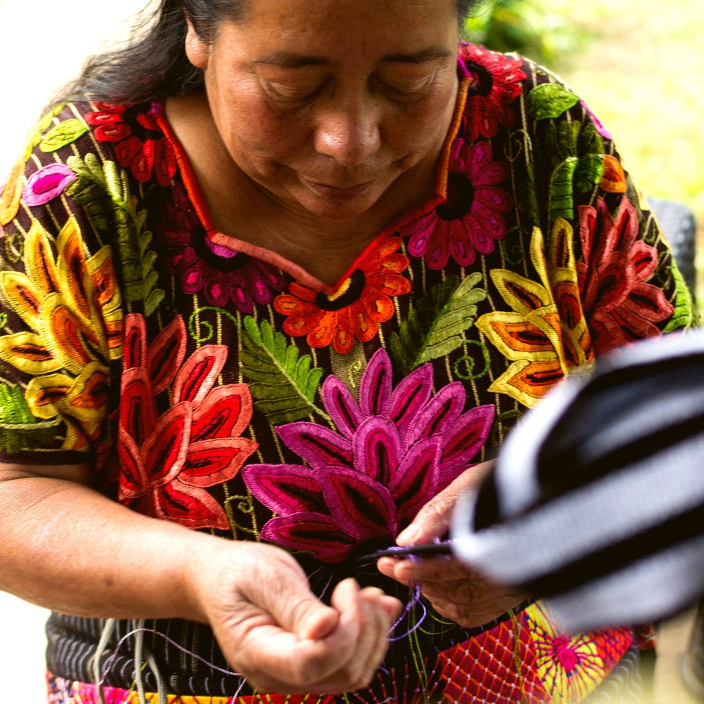 Woman in a colorful floral dress working with yarn outdoors
