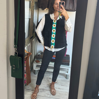 Person taking a mirror selfie wearing a black vest, white shirt, and dark pants.