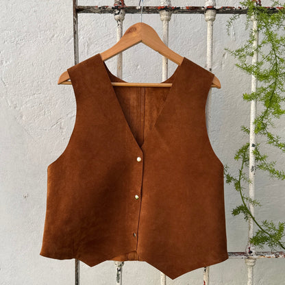 Brown vest on a hanger against a rustic wooden background