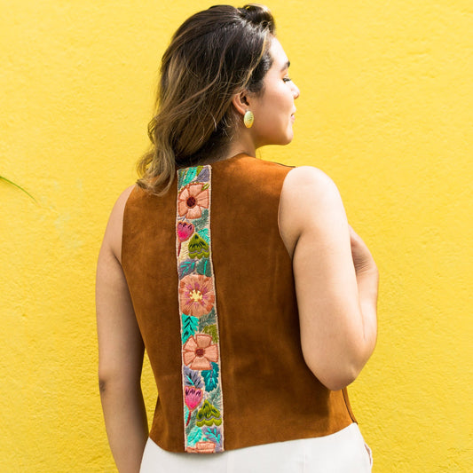 Woman wearing a brown sleeveless top with floral patterns on a yellow wall