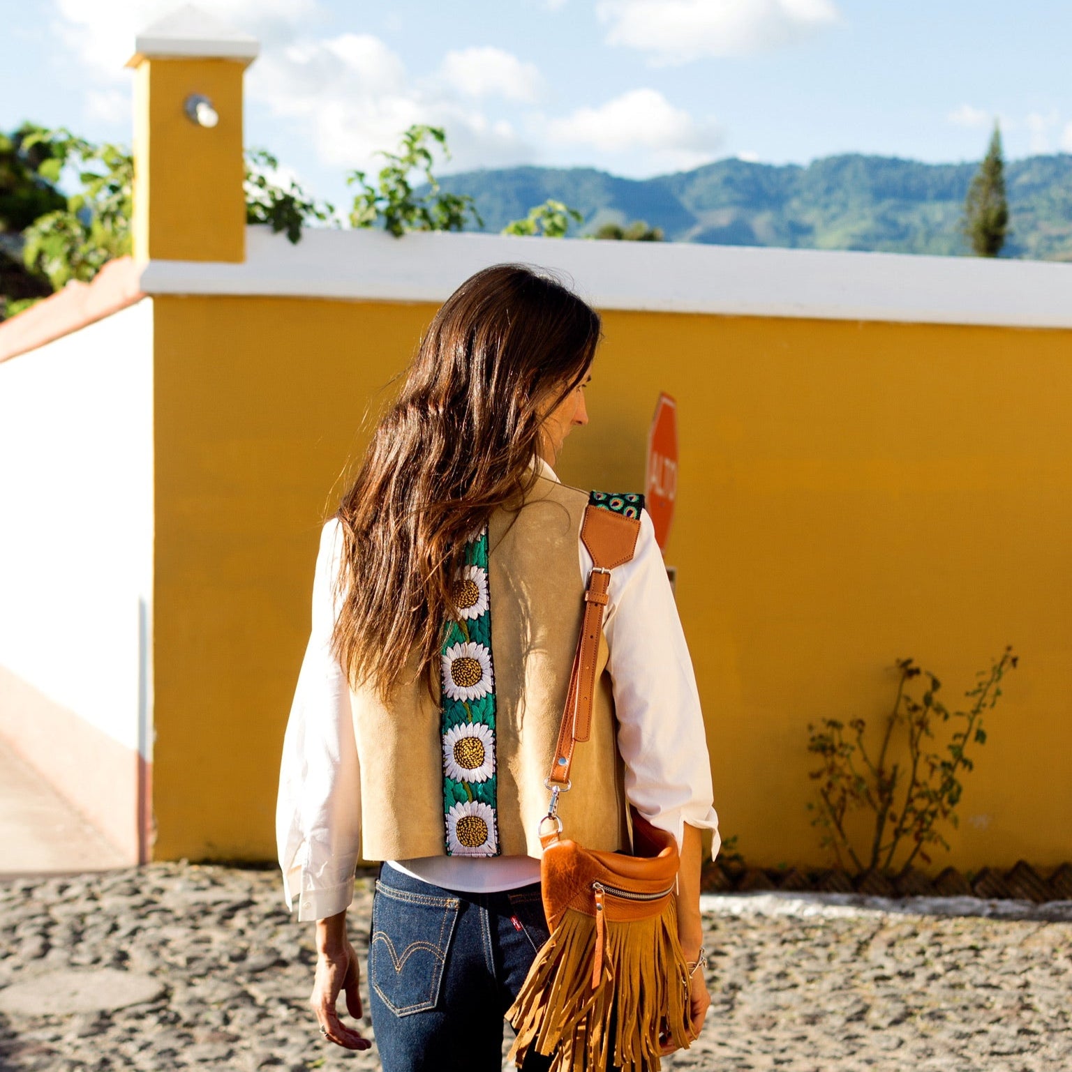 Woman standing in front of a yellow wall with mountains in the background
