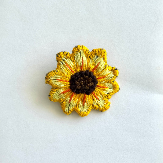 Yellow sunflower-shaped brooch on a white background
