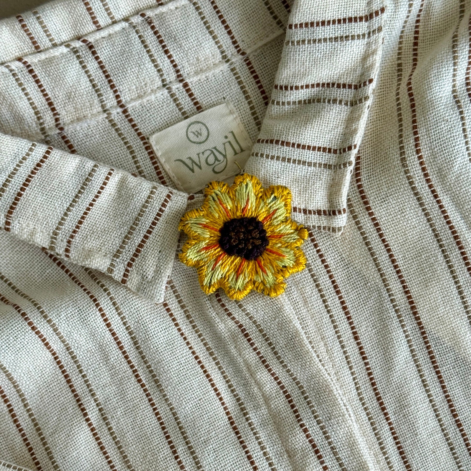 Striped fabric with a sunflower decoration and a visible brand label.