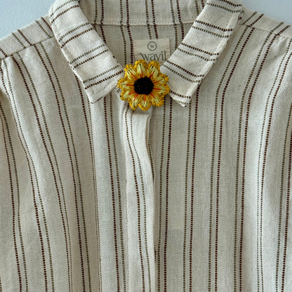 Striped shirt with a sunflower brooch on a light blue background