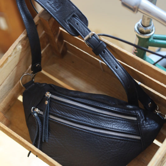 Black leather bag with zippers on a wooden surface