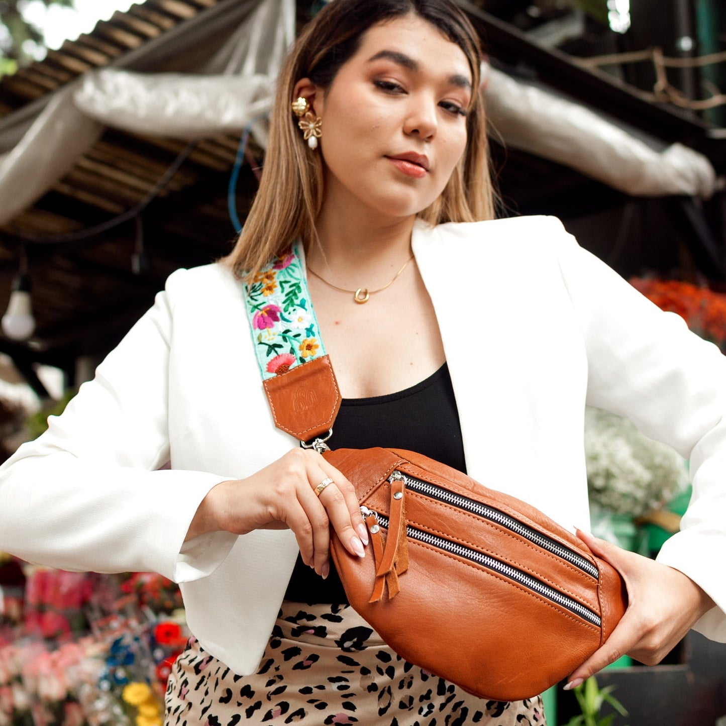 Woman holding a brown leather fanny pack with a blurred background