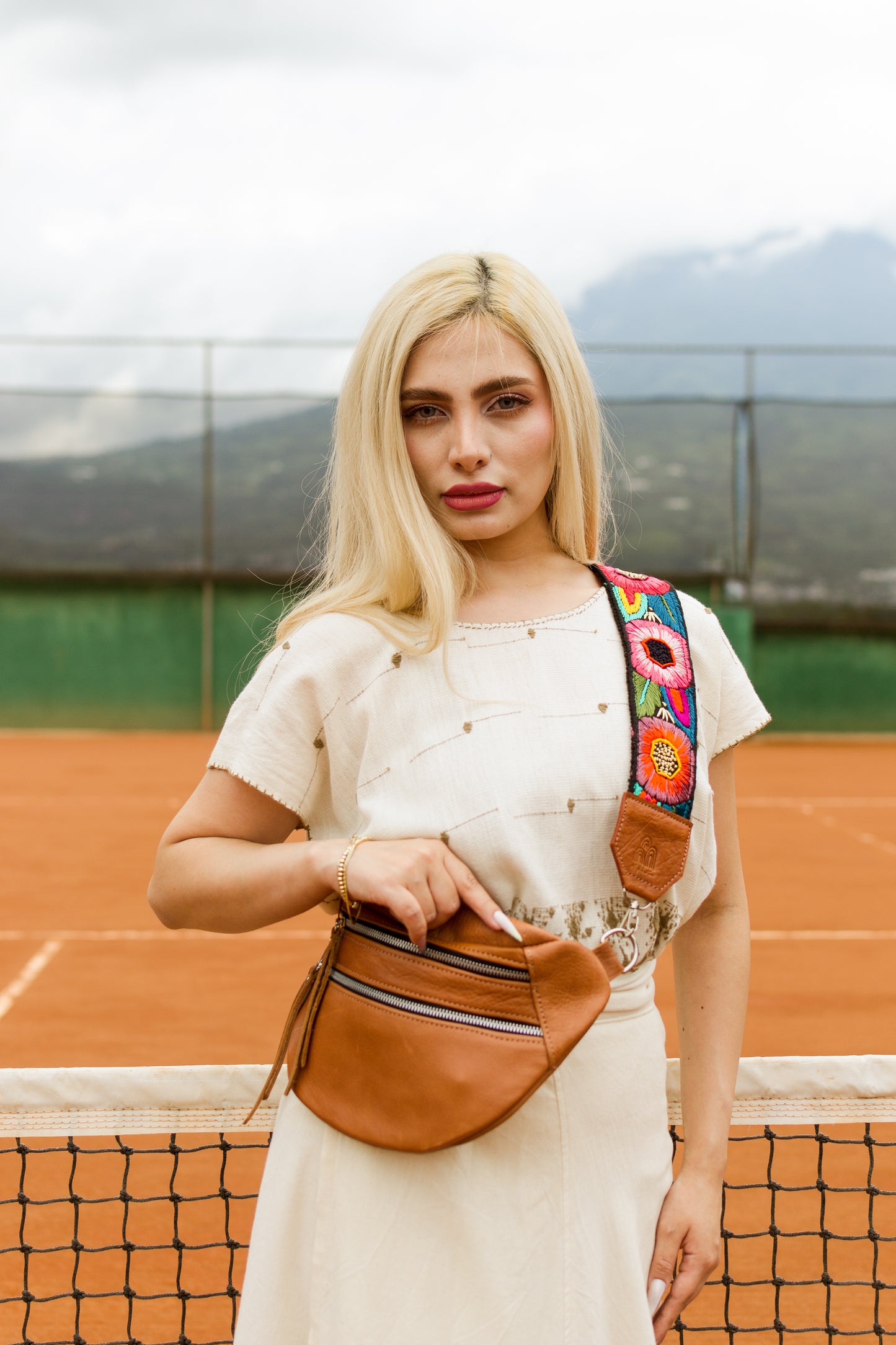 Woman with a colorful bag and brown fanny pack on a tennis court