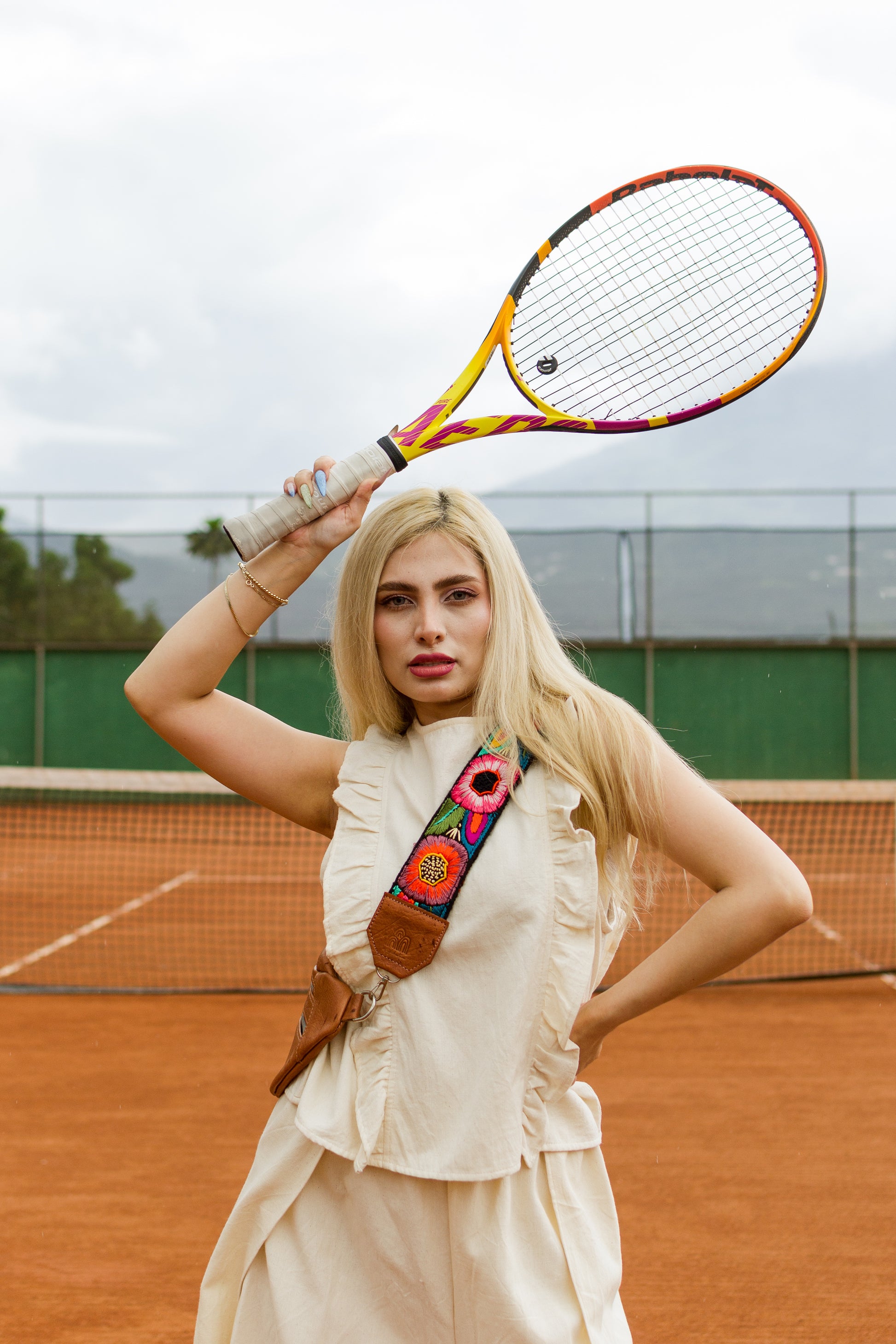 Woman holding a colorful tennis racket on a tennis court