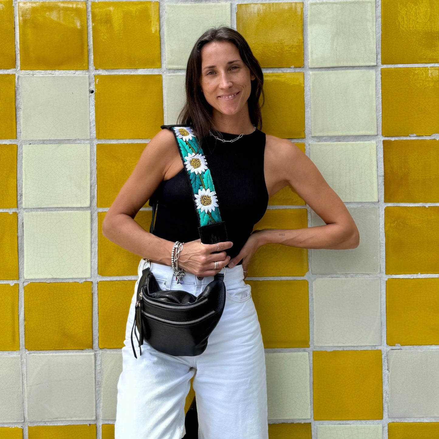 Woman holding a floral bag against a yellow and white tiled wall