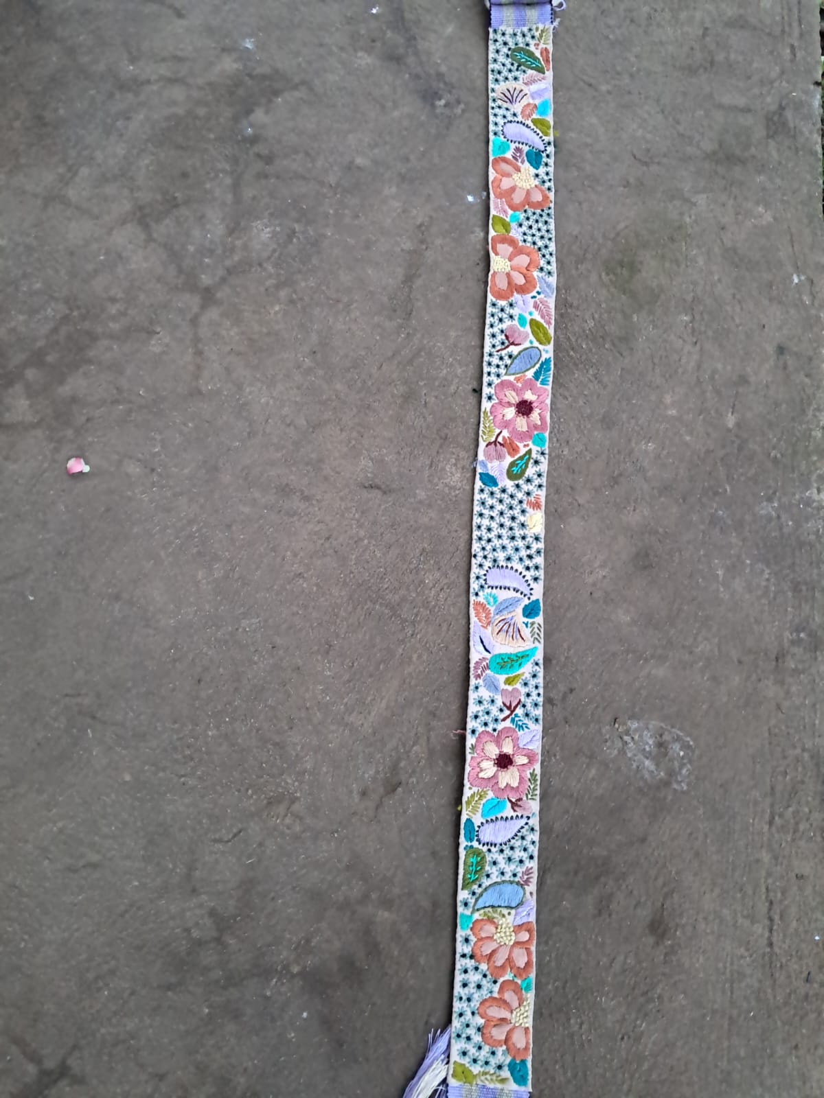 Floral-patterned belt on a gray concrete surface
