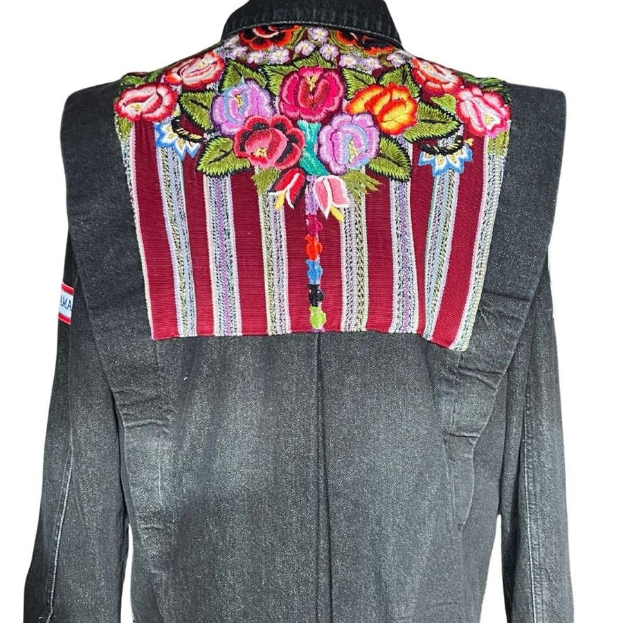Denim jacket with colorful floral embroidery on a mannequin against a white background
