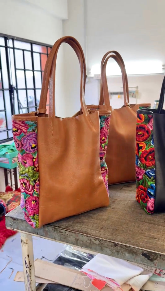 Two brown tote bags with colorful floral patterns on a metal table.