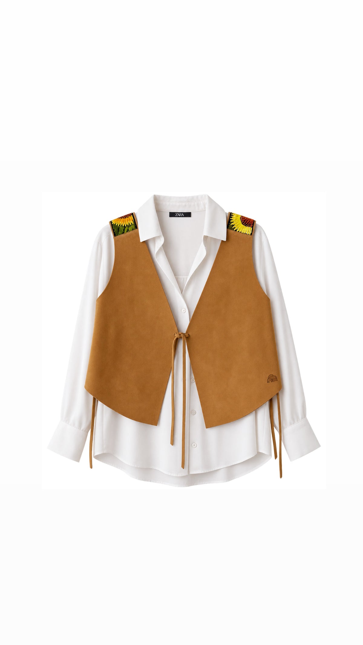 A tan suede vest with tie-front closure and fringe details, styled over a white button-down shirt. The vest features colorful embroidered details on the shoulders.