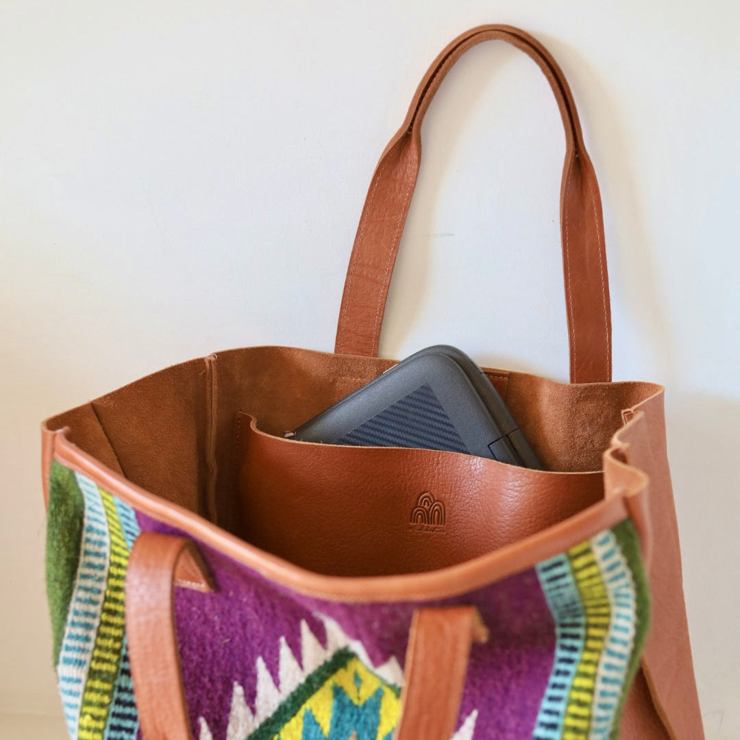 Tote bag with colorful patterned front and brown leather sides on a white background