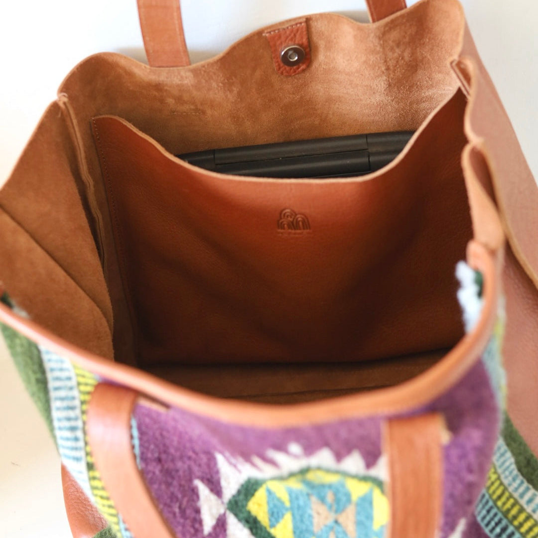 Brown leather handbag with colorful patterned strap on a white background