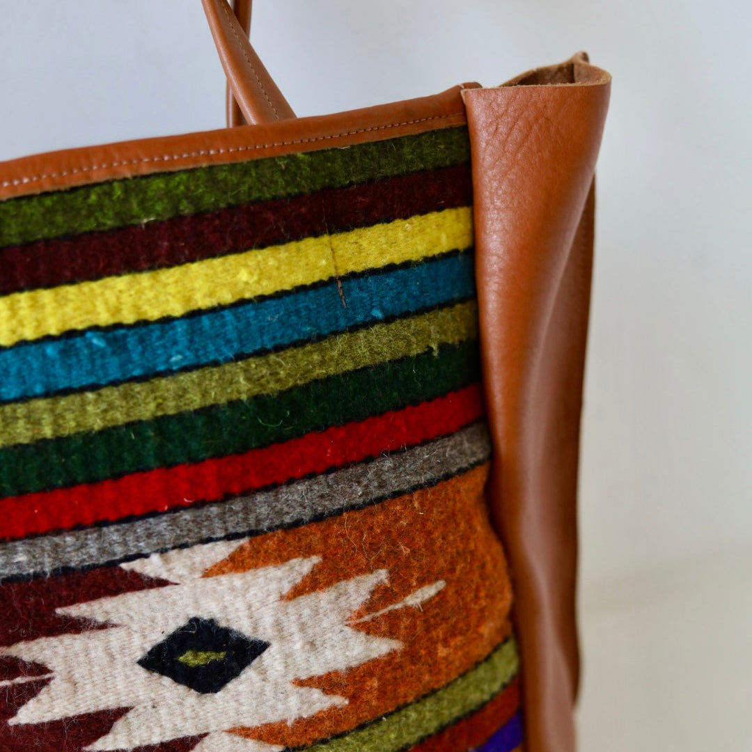 Colorful woven bag with a brown leather handle on a white background